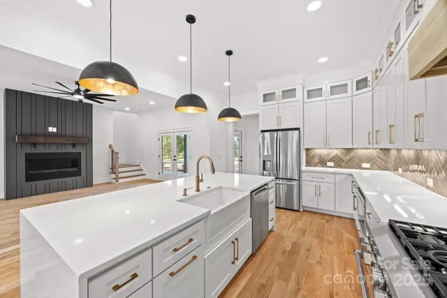 a kitchen with stainless steel appliances granite countertop a sink a stove and a wooden floors