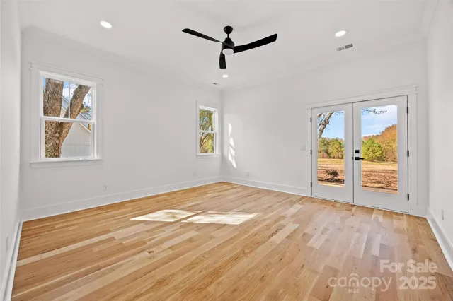 a view of empty room with wooden floor and ceiling fan