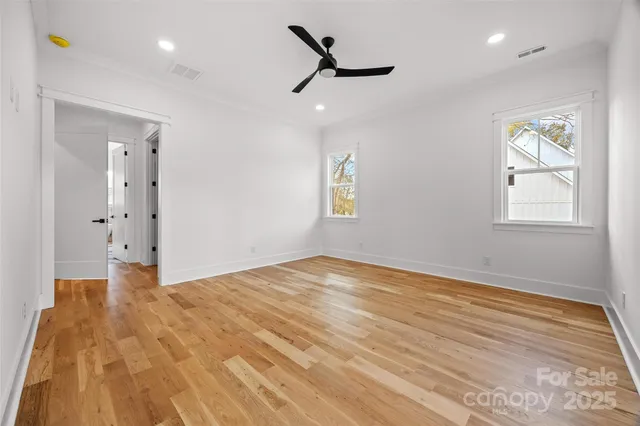 a view of empty room with wooden floor and fan