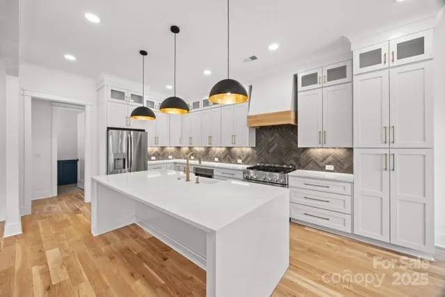 a kitchen that has a lot of white cabinets and stainless steel appliances