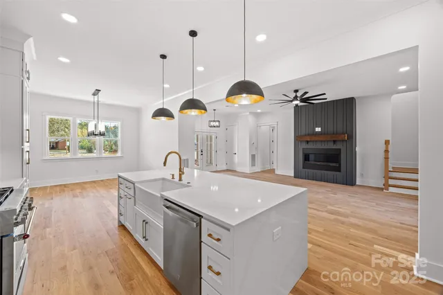 a large kitchen with stainless steel appliances granite countertop a sink a stove and a wooden floors