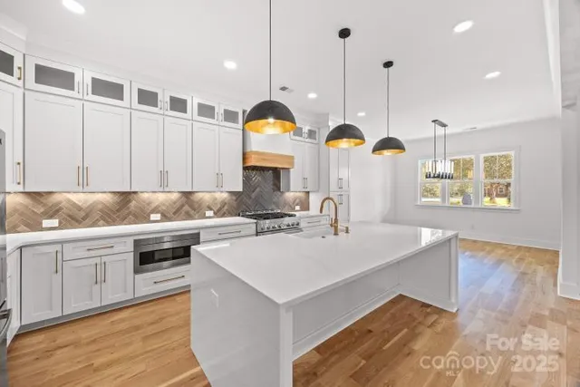 a kitchen with stainless steel appliances granite countertop a sink a stove and a wooden floors