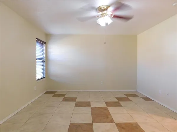an empty room with a chandelier fan and windows