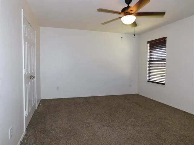 an empty room with a window and a fan