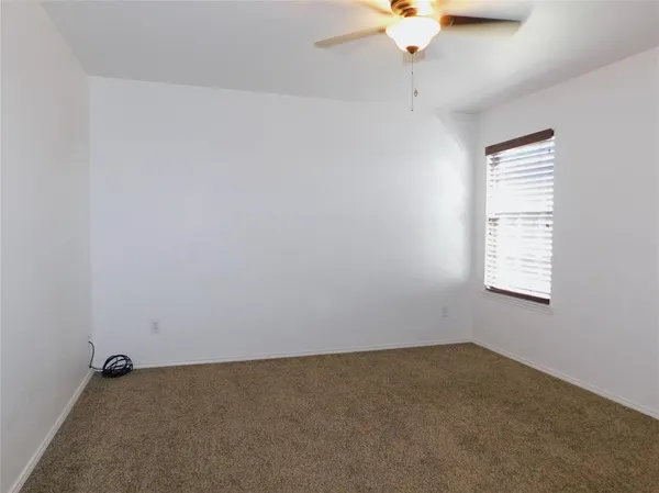an empty room with a ceiling fan and window