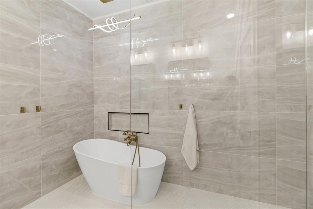 435 Waterboard Road Trinidad, TX 75163 - Photo 34 of 39 Freestanding bathtub with brass-finish fixtures set against large format wall tiling