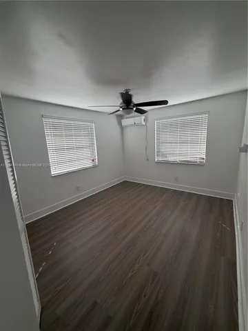 an empty room with wooden floor cabinet and windows
