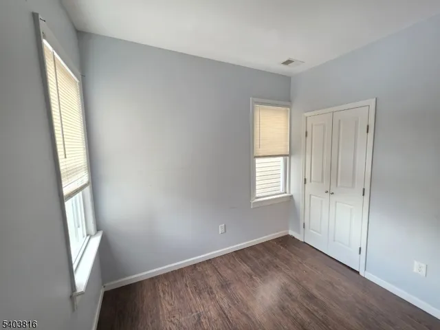 a view of an empty room with wooden floor and window