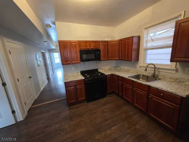 a kitchen with granite countertop wooden cabinets a sink a window and stainless steel appliances