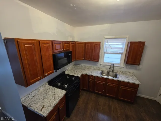 a kitchen with granite countertop sink cabinets and wooden floor