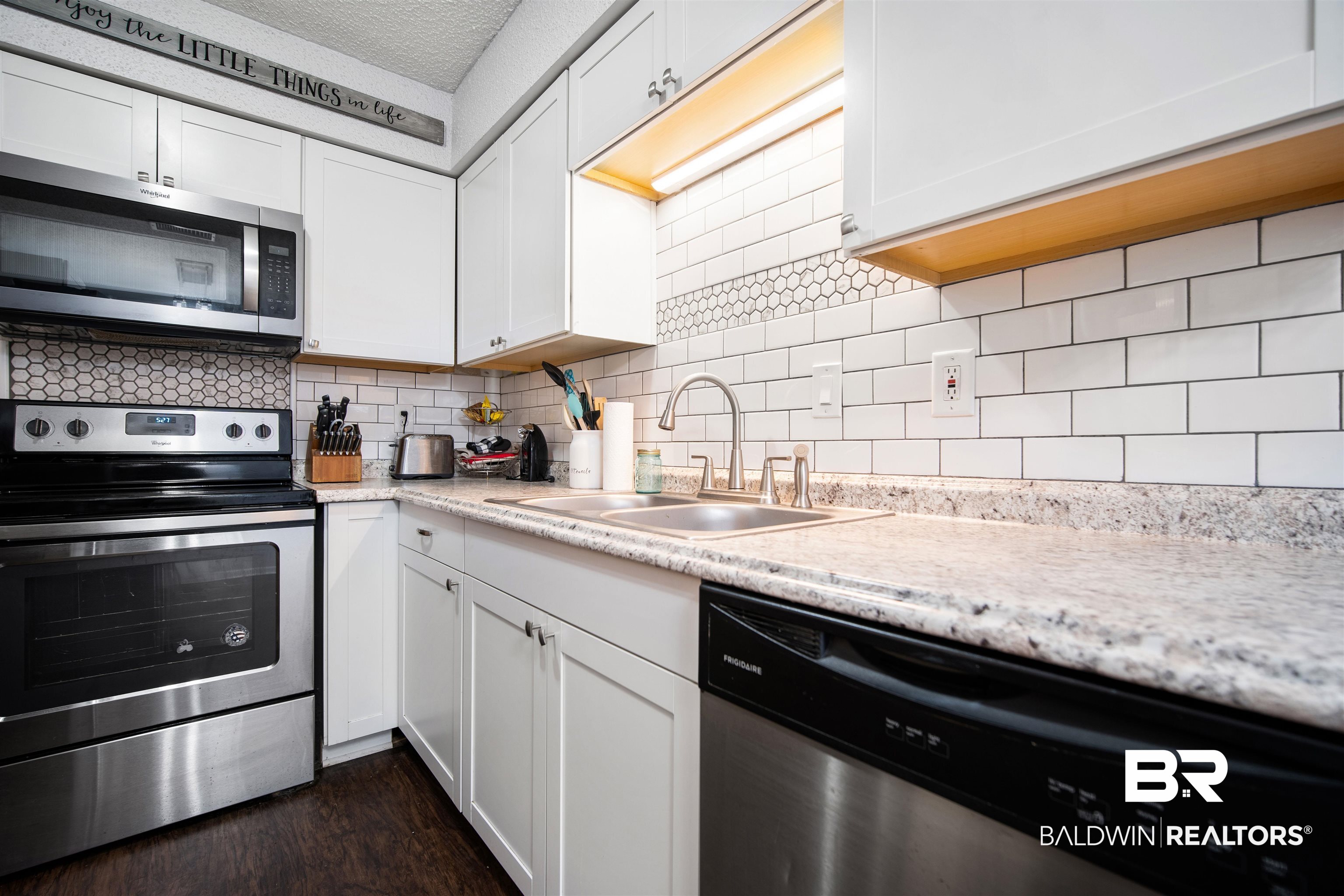 5110 Wilmer Road Wilmer, AL 36587 - Photo 7 of 24 Kitchen featuring appliances with stainless steel finishes, dark hardwood / wood-style flooring, tasteful backsplash, sink, and white cabinetry