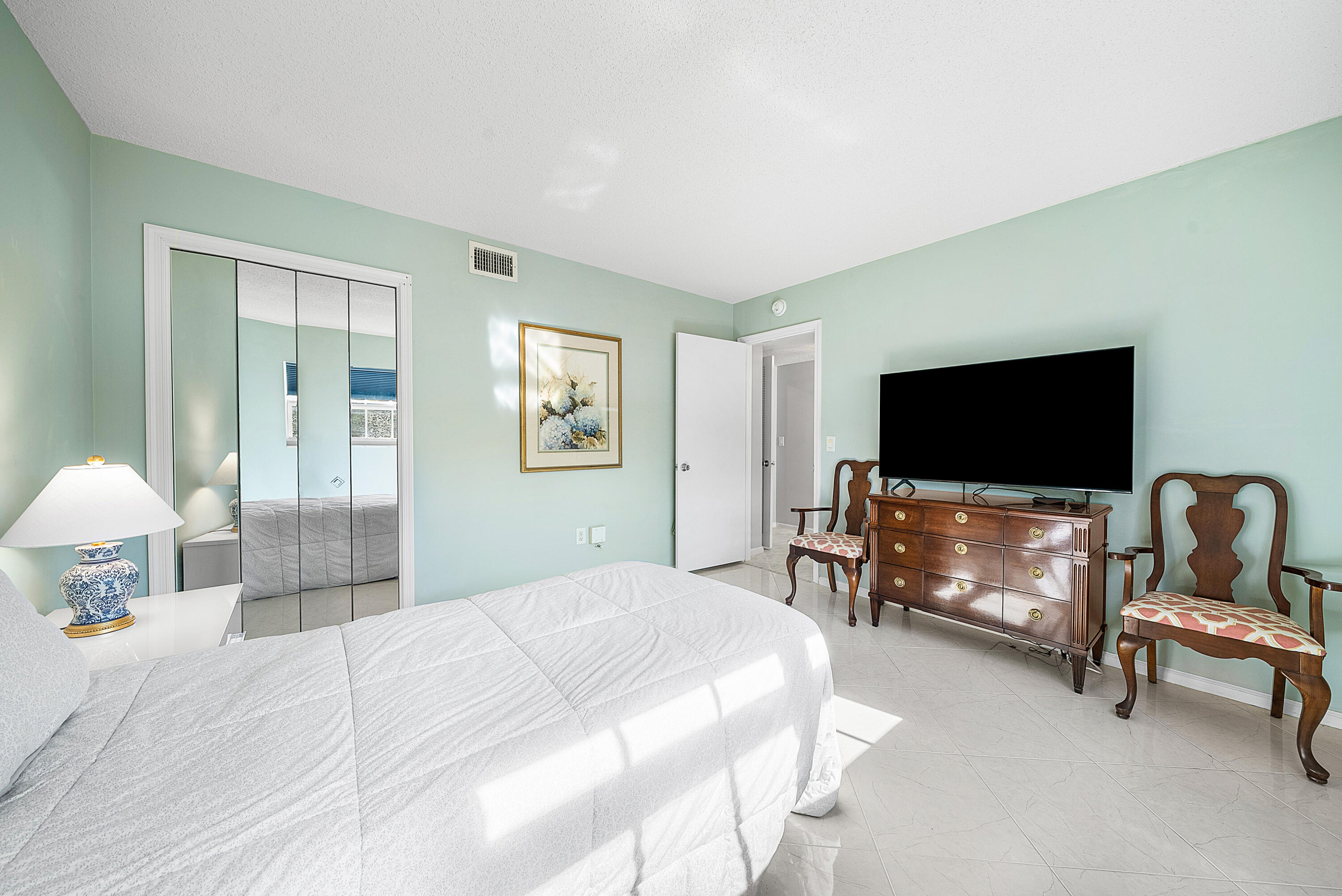 145 Atlantis Boulevard, Unit 201 Atlantis, FL 33462 - Photo 17 of 40 a bedroom with bed and a flat screen tv