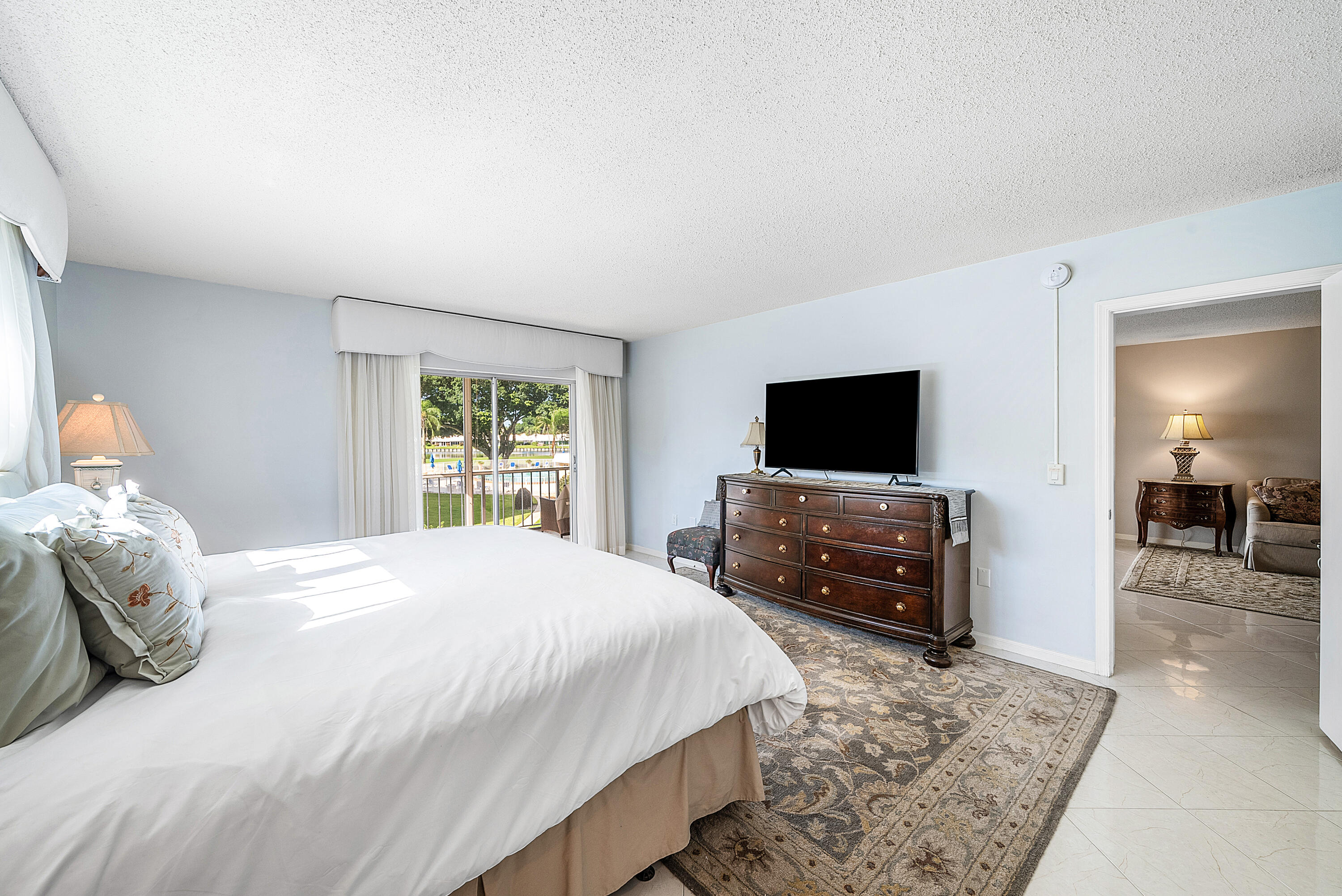 145 Atlantis Boulevard, Unit 201 Atlantis, FL 33462 - Photo 21 of 40 a bedroom with a bed and a flat screen tv