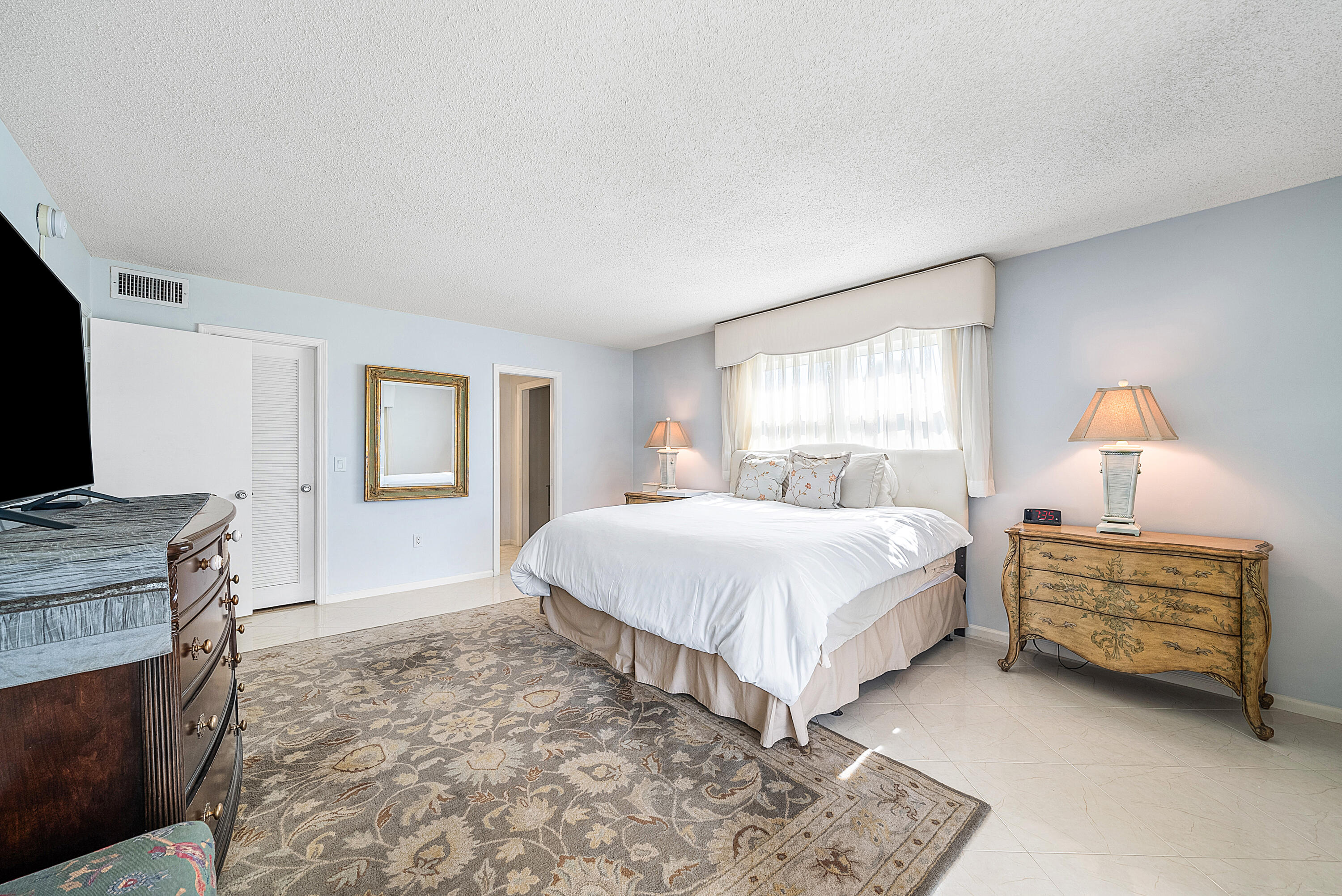 145 Atlantis Boulevard, Unit 201 Atlantis, FL 33462 - Photo 25 of 40 a spacious bedroom with a bed and a flat screen tv