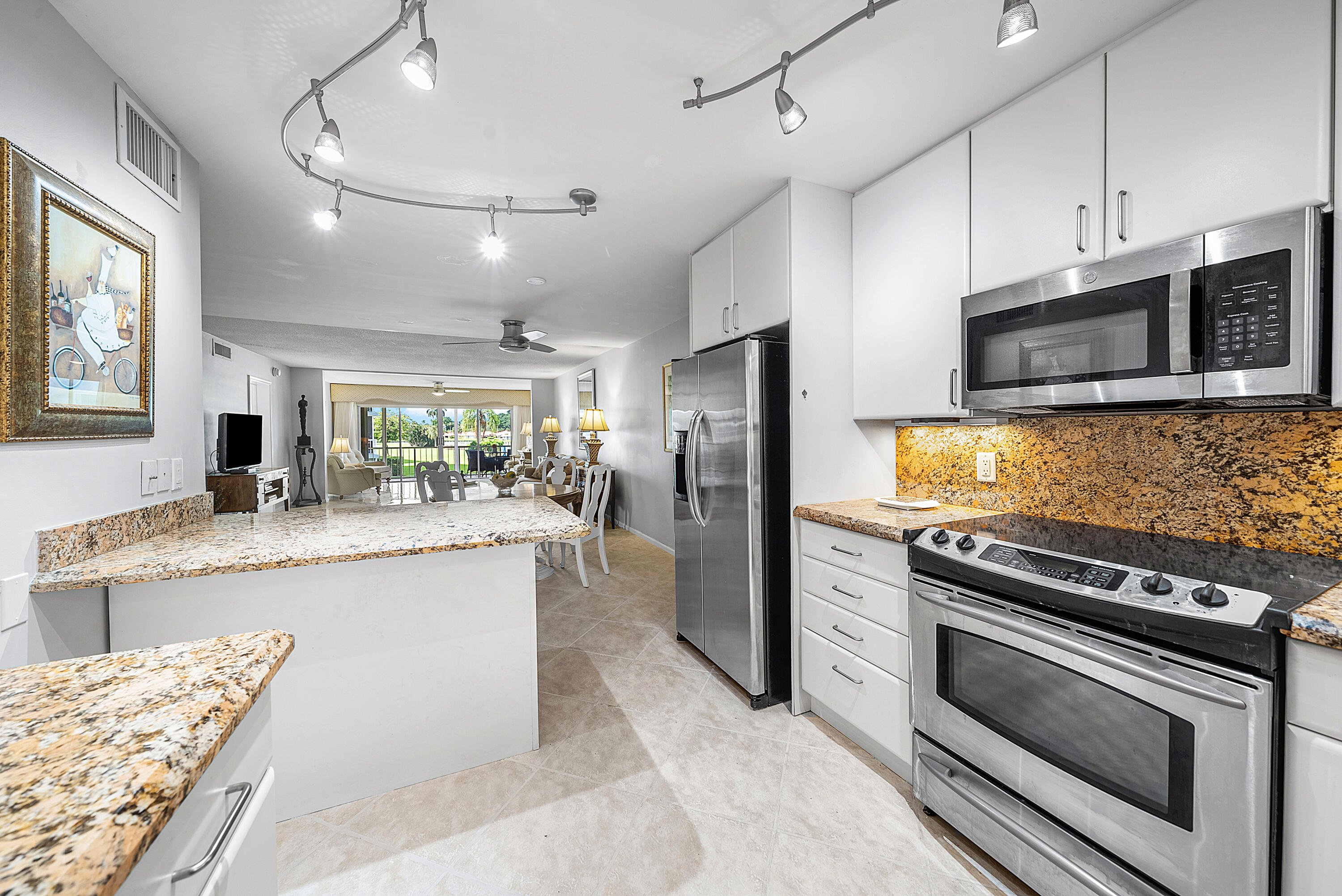 145 Atlantis Boulevard, Unit 201 Atlantis, FL 33462 - Photo 8 of 40 a kitchen with stainless steel appliances kitchen island granite countertop a stove refrigerator and microwave