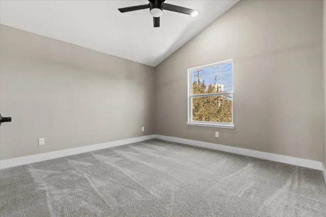 an empty room with ceiling fan and window