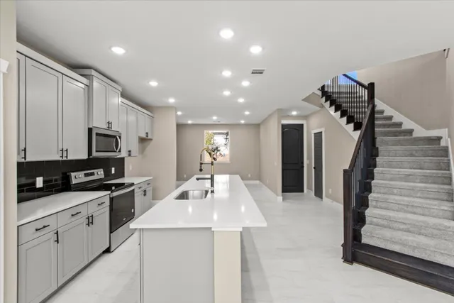 a kitchen with granite countertop a sink stainless steel appliances and cabinets