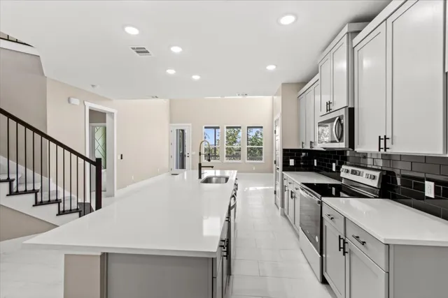 a large white kitchen with lots of counter space a sink and appliances