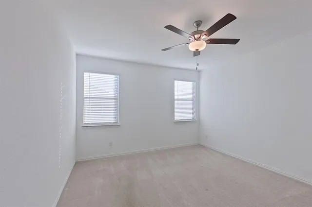 an empty room with a ceiling fan and window