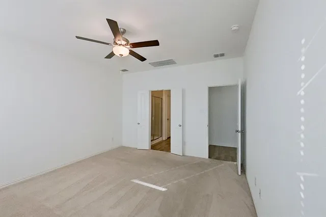 a bedroom with a ceiling fan and a bathroom