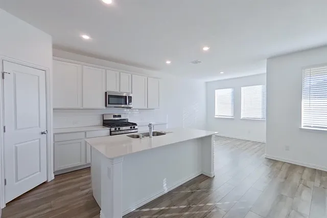 a kitchen with granite countertop white cabinets and stainless steel appliances