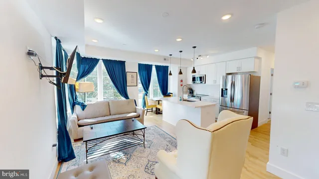 a living room with stainless steel appliances furniture a rug and a window