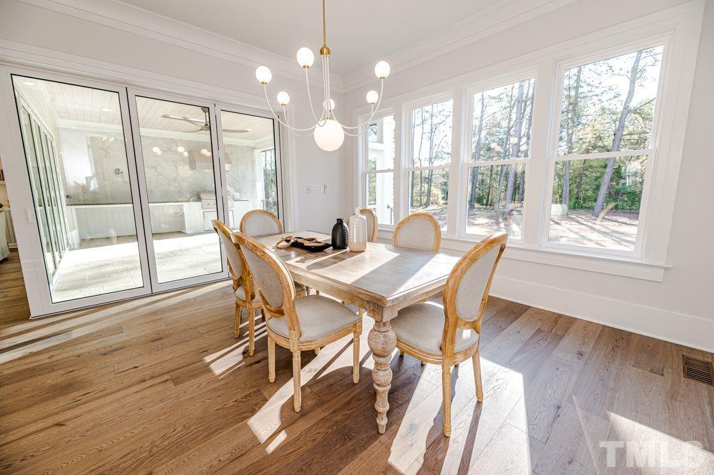 1501 Kirkby Lane Raleigh, NC 27614 - Photo 18 of 54 a dining room with wooden floor a chandelier a glass table and chairs