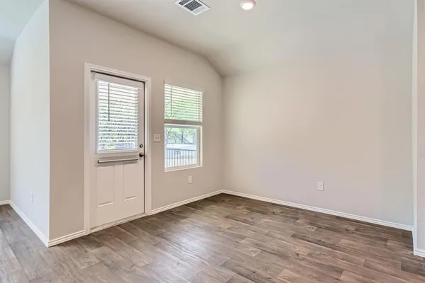 an empty room with wooden floor and windows