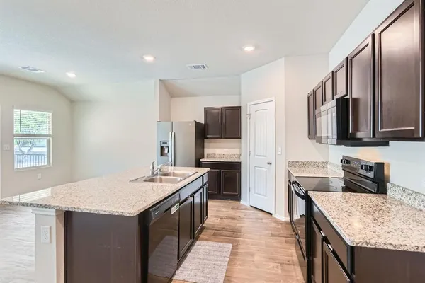 a kitchen with stainless steel appliances granite countertop a sink stove microwave and refrigerator