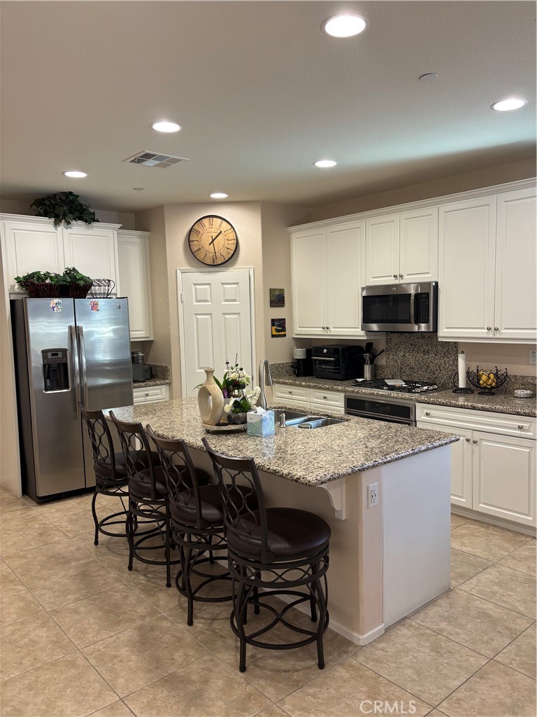2534 Mapleleaf Terrace Palmdale, CA 93551 - Photo 7 of 48 a kitchen with stainless steel appliances granite countertop a table chairs sink and cabinets