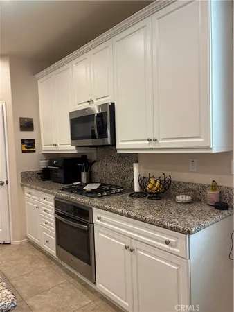 a kitchen with granite countertop white cabinets and stainless steel appliances