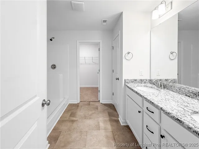 a spacious bathroom with a granite countertop sink a mirror and a bathtub