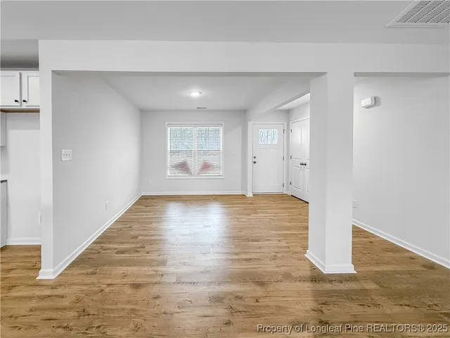 an empty room with wooden floor and windows