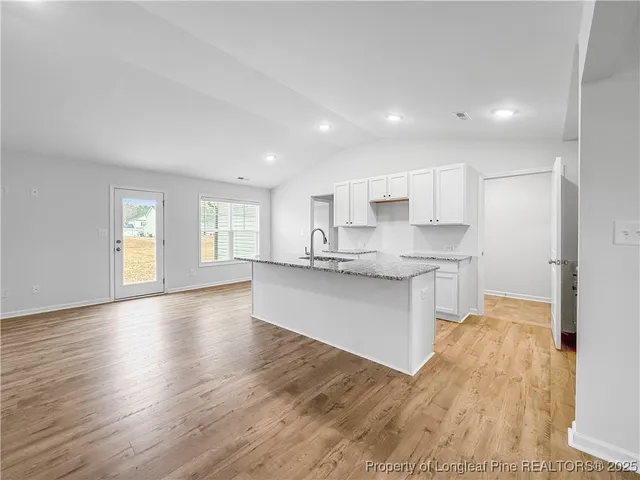 a large kitchen with white cabinets and wooden floor