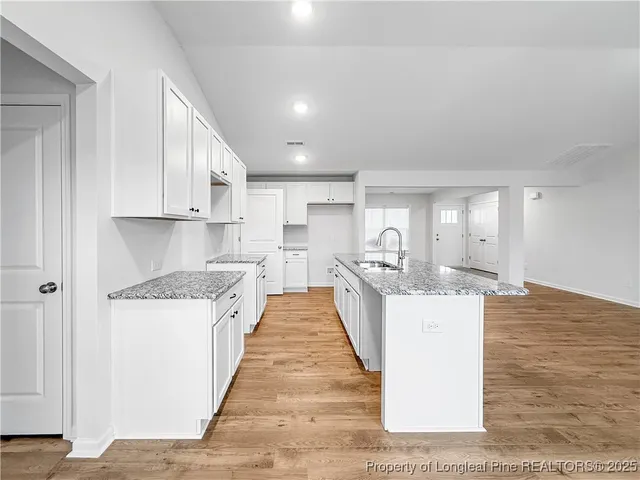 a view of a kitchen with kitchen island a sink a stove and a wooden floors