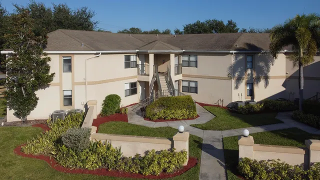 a view of a white house with a yard and potted plants