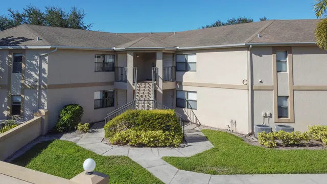 a view of a white house with a yard and potted plants