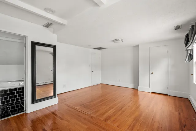 a view of an empty room with a window and wooden floor