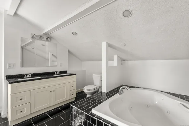 a bathroom with a granite countertop sink and a toilet