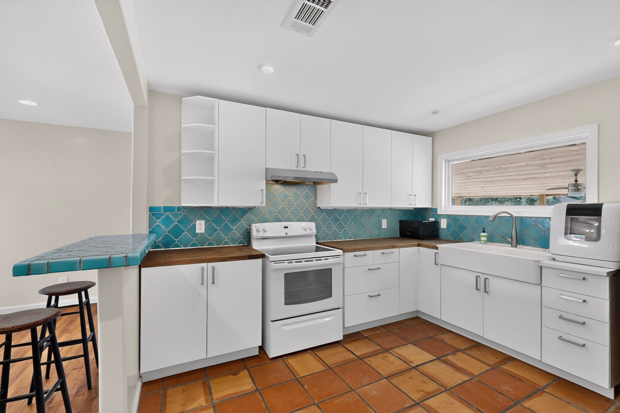 4711 Alf Avenue Austin, TX 78721 - Photo 11 of 34 A well-equipped kitchen boasts white cabinetry, wood countertops, and terra cotta tiled flooring.