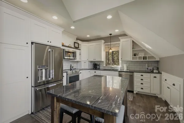 a large kitchen with kitchen island a large counter top space appliances and cabinets