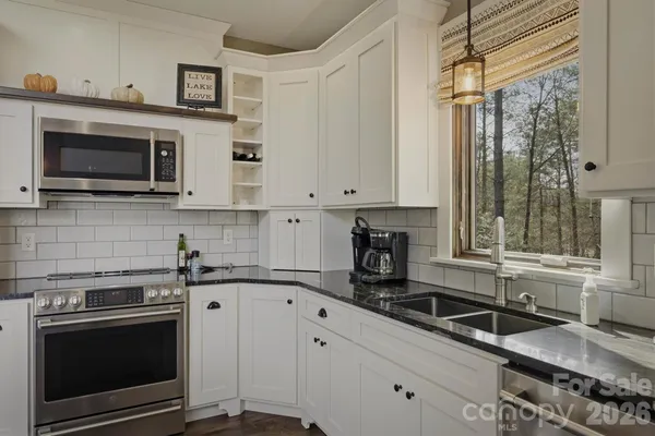 a kitchen with granite countertop a stove a sink and a microwave