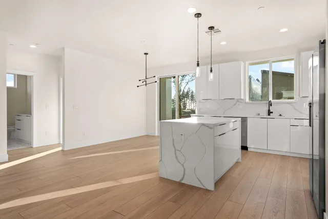 a kitchen with stainless steel appliances granite countertop a sink a stove a refrigerator and white cabinets