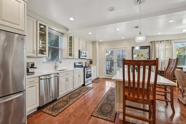a large kitchen with kitchen island wooden floors wooden cabinets a center island and stainless steel appliances