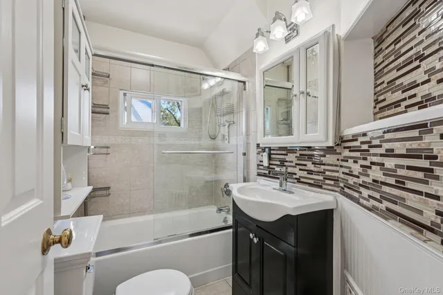 a bathroom with a sink a toilet a mirror a bathtub and shower