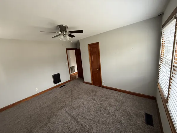 an empty room with windows and fan