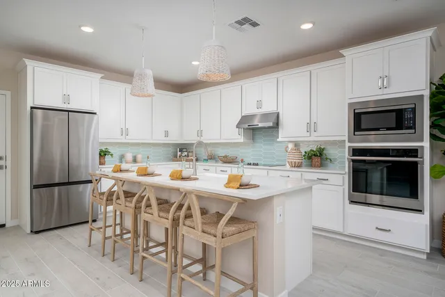 a kitchen with stainless steel appliances granite countertop a refrigerator and white cabinets