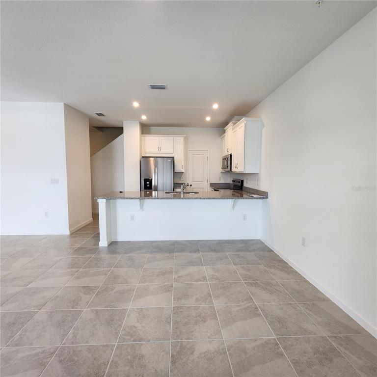 4232 Sadler Road Apopka, FL 32712 - Photo 5 of 31 a large white kitchen with kitchen island granite countertop a large counter top and a sink