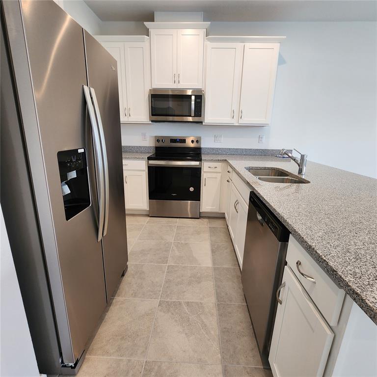 4232 Sadler Road Apopka, FL 32712 - Photo 9 of 31 a kitchen with stainless steel appliances granite countertop a refrigerator a stove a sink and a microwave