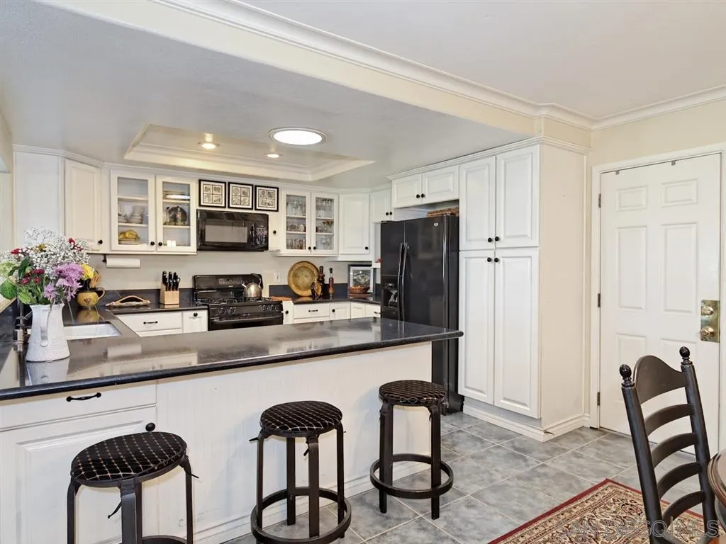 1718 West Knapp Drive Vista, CA 92083 - Photo 7 of 24 a kitchen with stainless steel appliances kitchen island granite countertop a refrigerator a stove a sink dishwasher and white cabinets with wooden floor